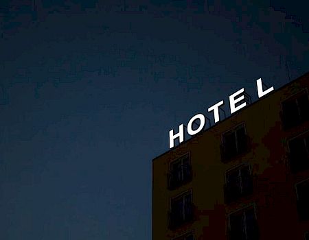 A building with the word "HOTEL" illuminated at the top against a dark sky.