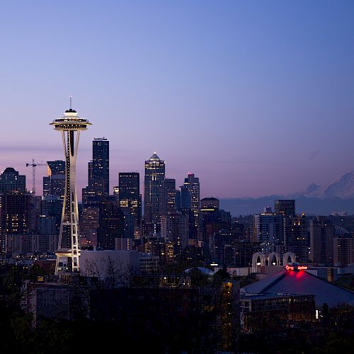 Seattle skyline at dusk with the Space Needle and Mount Rainier visible in the background.